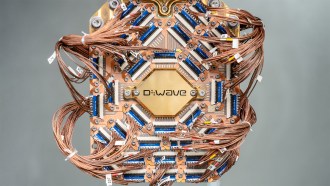 A piece of computer hardware shows a lot of wires surrounding a D-Wave logo.